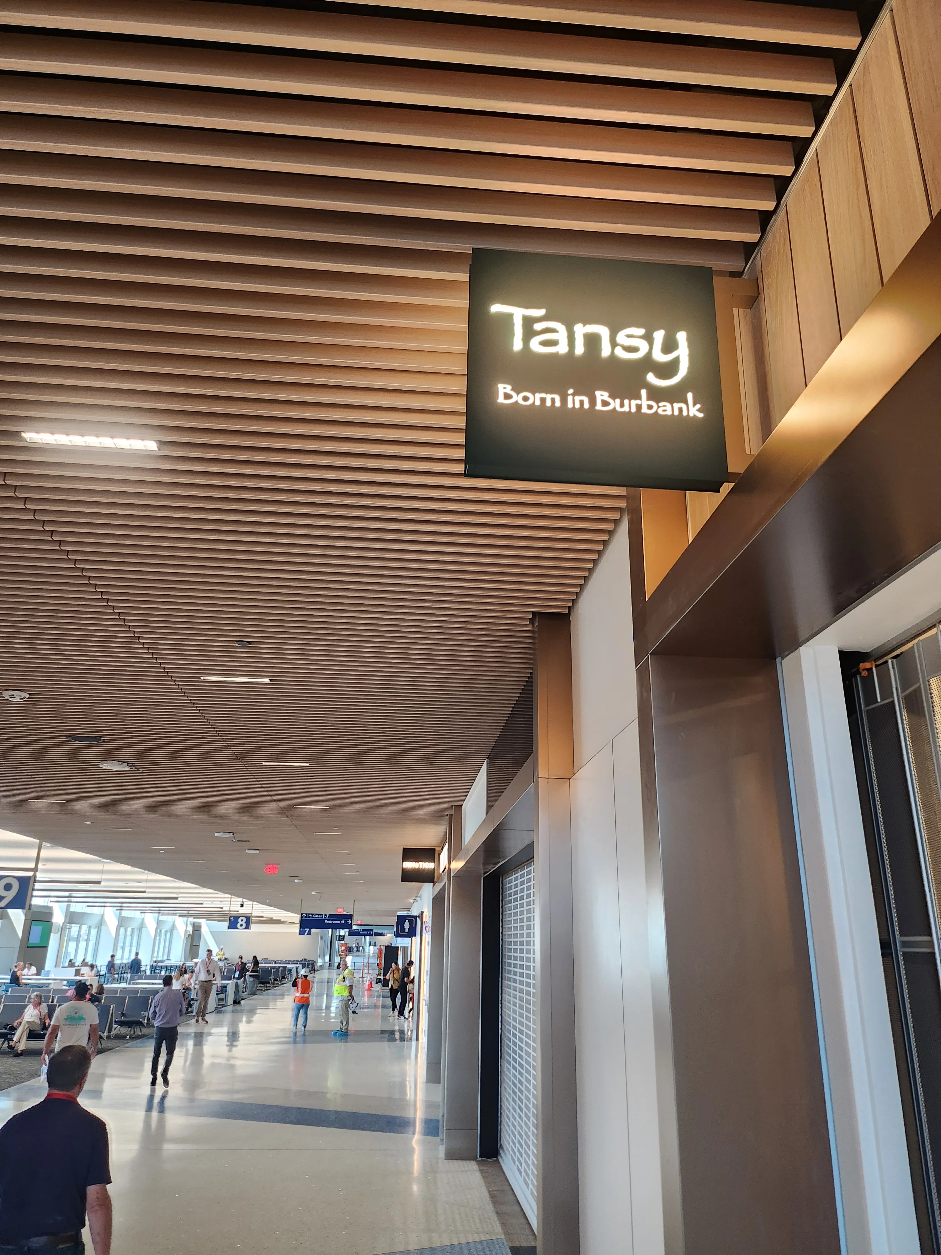 A backlit sign for Tansy, reading Born in Burbank, above the gate concourse